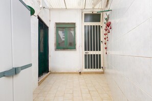 A narrow corridor with a tiled floor, a green door, a window with a white frame, and a barred door. - 2743 Appartamento Ros by Barbarhouse (Porto Cesareo)