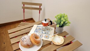 A wooden table with a plate of donuts, a teapot, a small potted plant, and a decorative shell. - 4bnb - Spacious Belli Apartment (Rome)