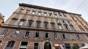 A multi-story building with a classic architectural style, featuring numerous windows and a central entrance. - 4bnb - Spacious Belli Apartment (Rome)