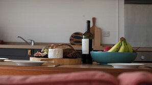 A kitchen counter with a bottle of wine, a bowl of fruit, and a loaf of bread. - Murmur y Coed (Llanfairpwllgwyngyll)