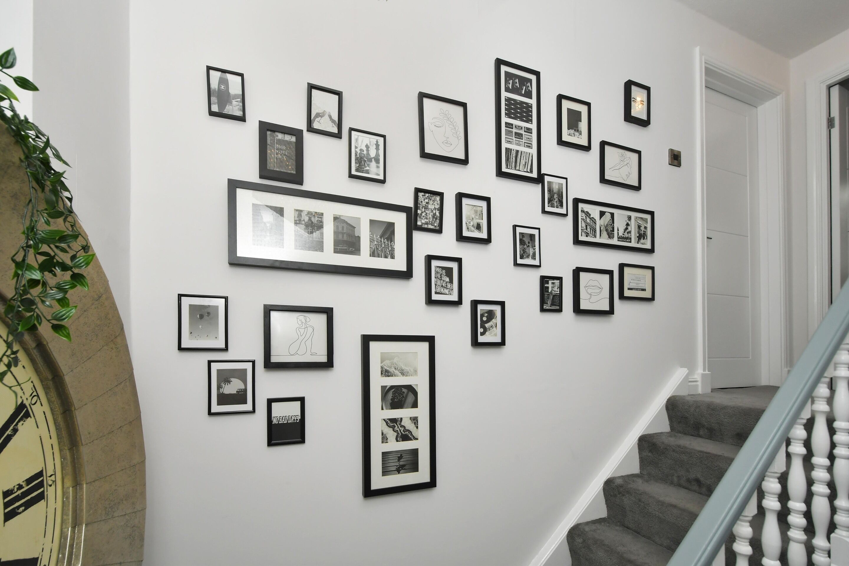 Un escalier muni d’une rampe et d’un mur orné de nombreuses photographies encadrées.