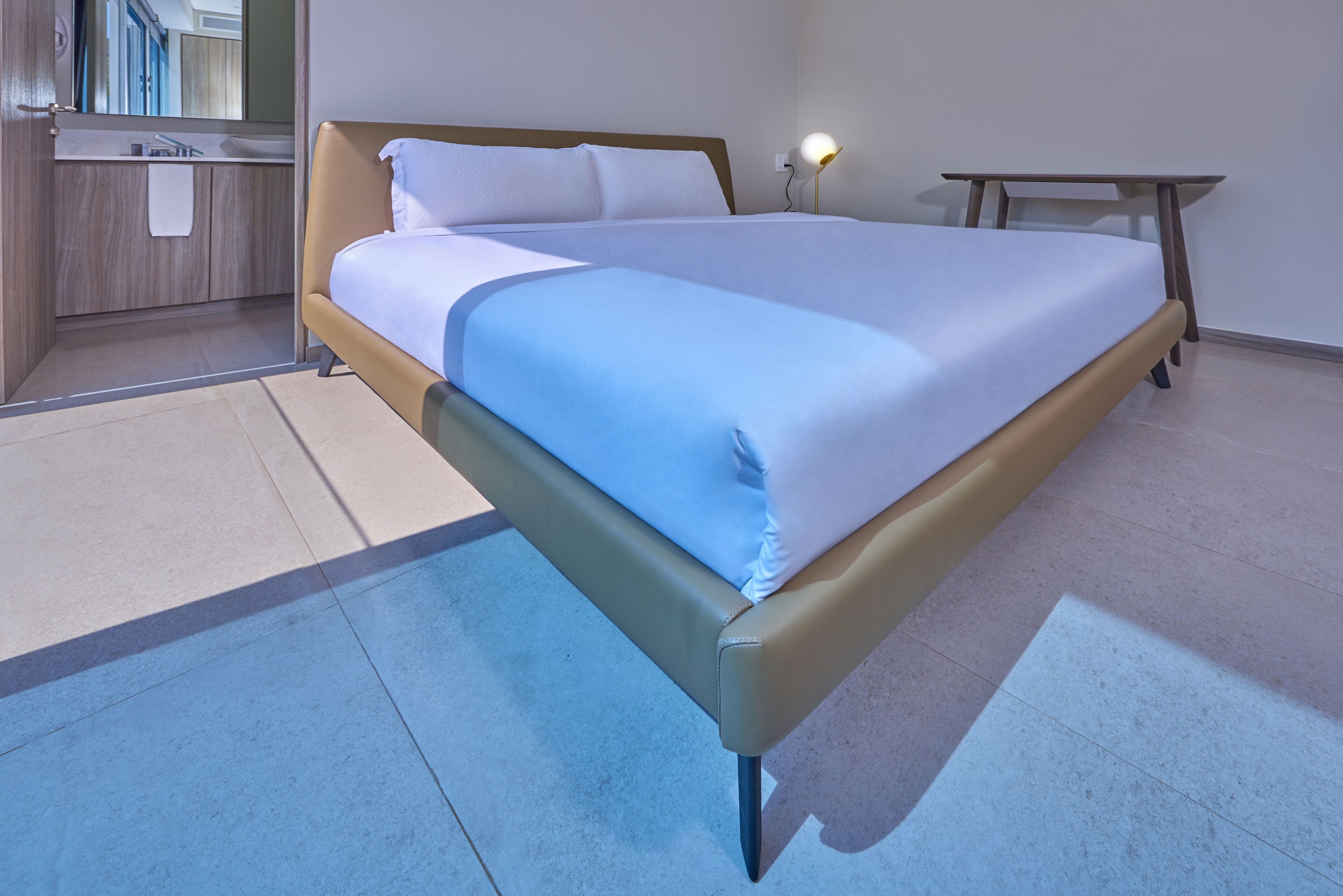 Una habitación de hotel moderna con una cama grande, una mesita de noche y un escritorio pequeño.