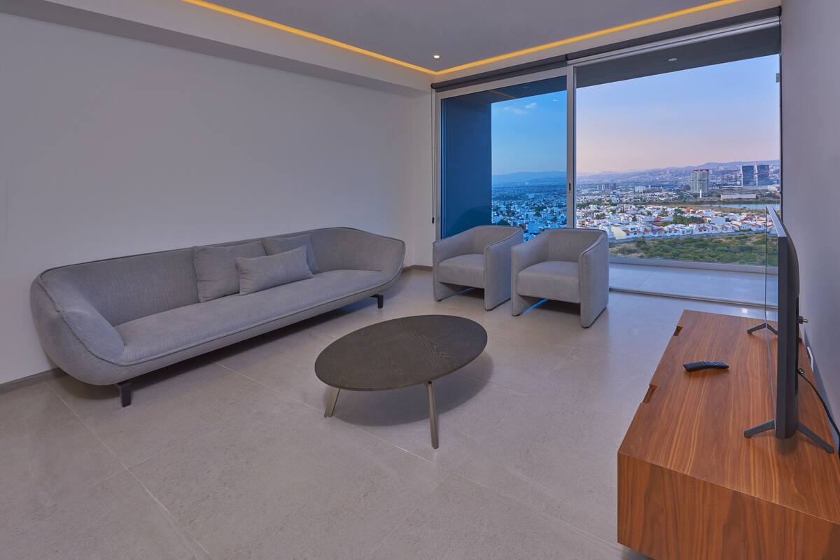 A modern living room with a grey sofa, two armchairs, a coffee table, and a wooden side table.