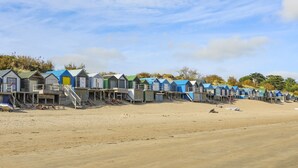 Een rij strandhutten met houten trappen die ernaar leiden, gelegen op een zandstrand.