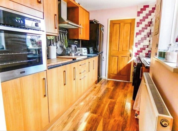 Kitchen equipped with oven, microwave, and wooden cabinetry.