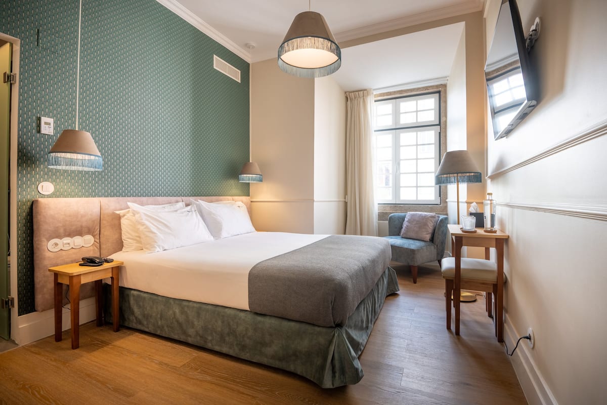 Une chambre d’hôtel avec un grand lit, des lampes de chevet, une petite table et un téléviseur fixé au mur.