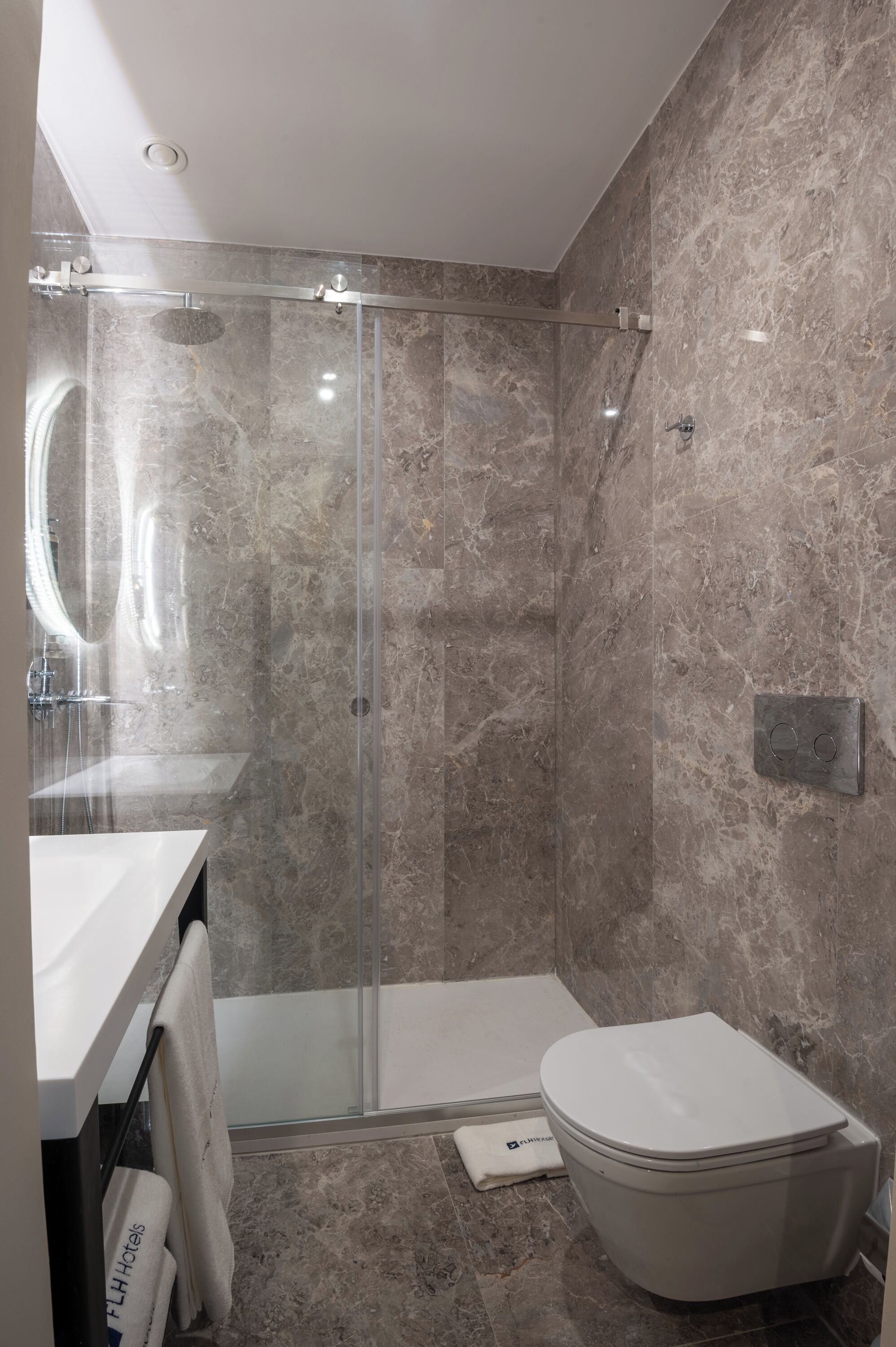 Une salle de bain moderne avec une douche à parois de verre, un lavabo blanc et des toilettes.