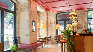 Een gezellig interieur met een rode plafond, een houten bank, een tafel met stoelen en een bar met een plant.
