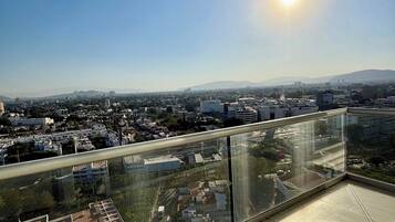Een hoog gebouw met een glazen balkon met uitzicht op een stadsgezicht.