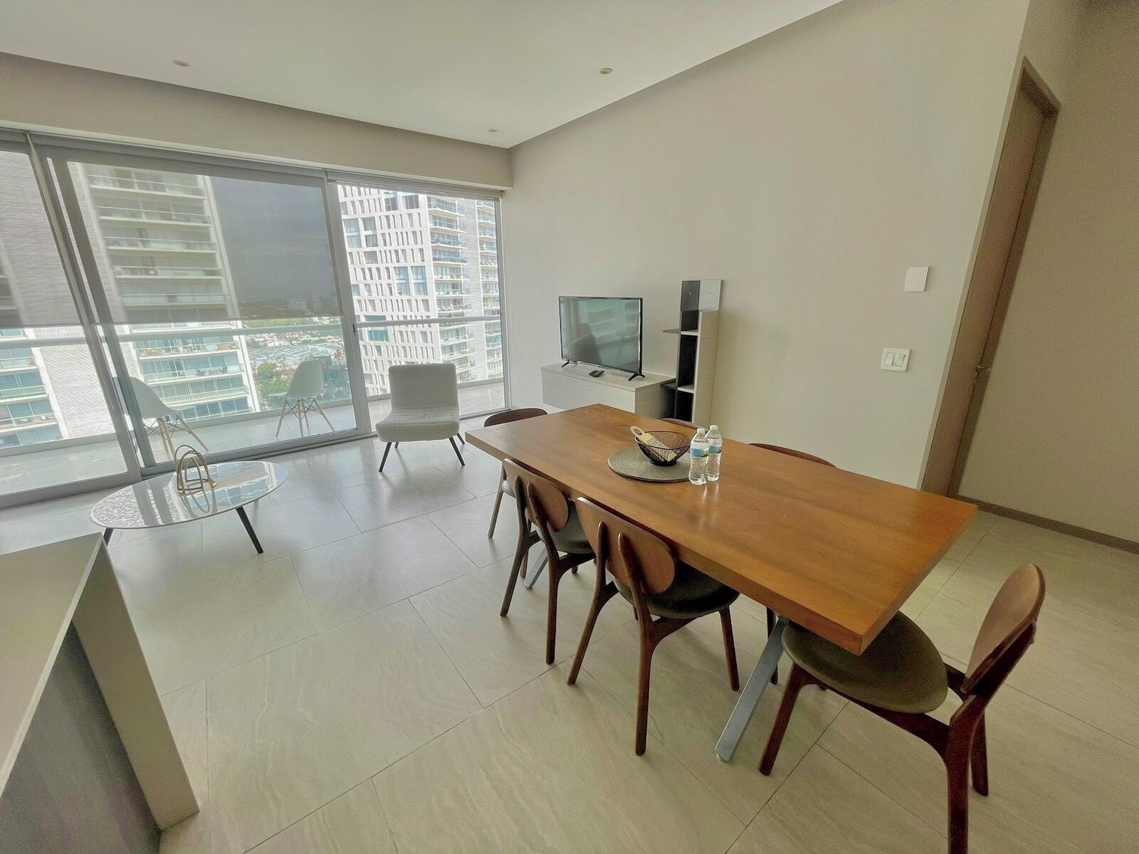 A modern dining area with a wooden table, chairs, and a TV.