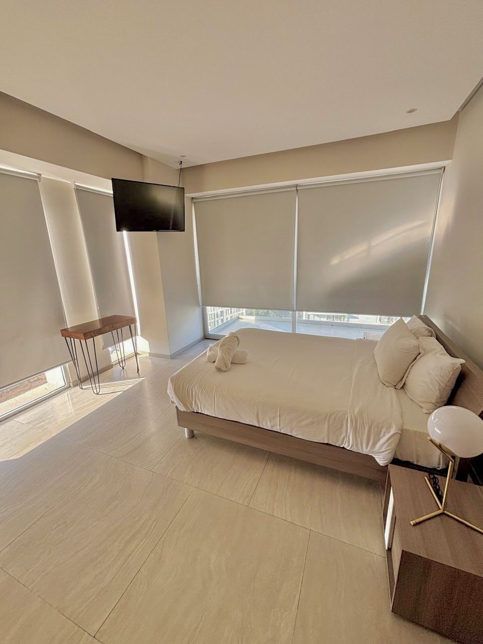 Une chambre moderne avec un grand lit, un téléviseur fixé au mur et un balcon avec vue.