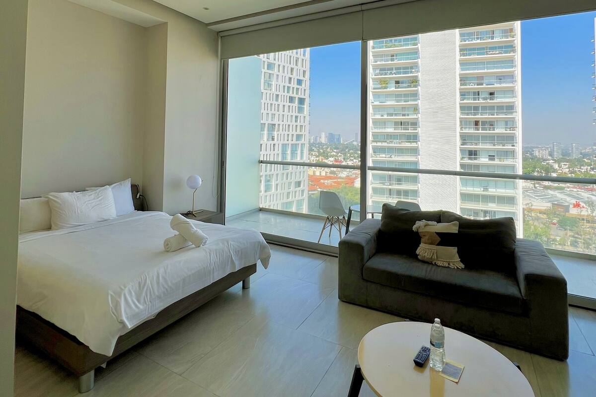 Una habitación de hotel moderna con cama, sofá y una mesa redonda.