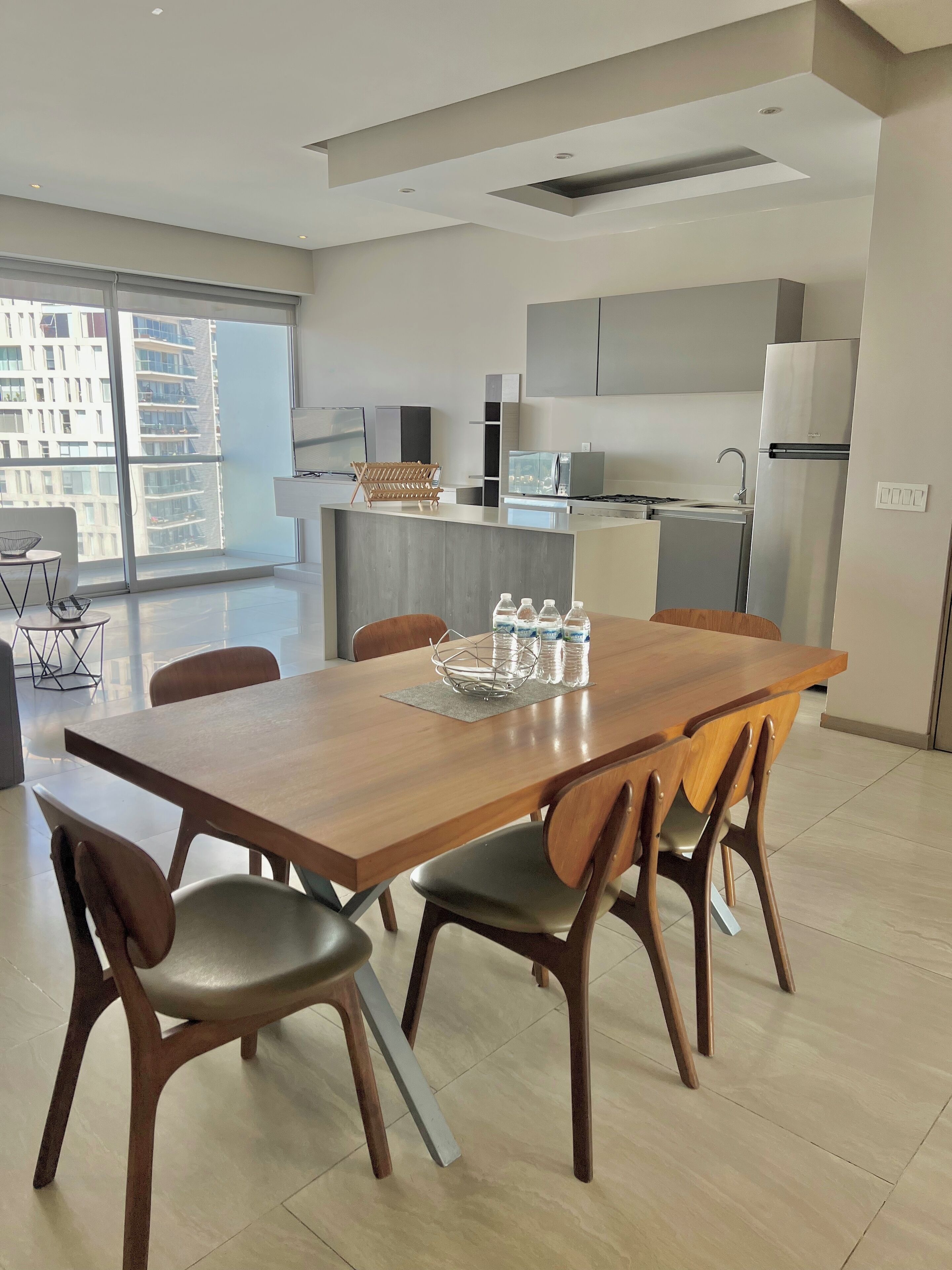 A modern kitchen with a central island, stainless steel appliances, and a dining area with a wooden table and chairs.