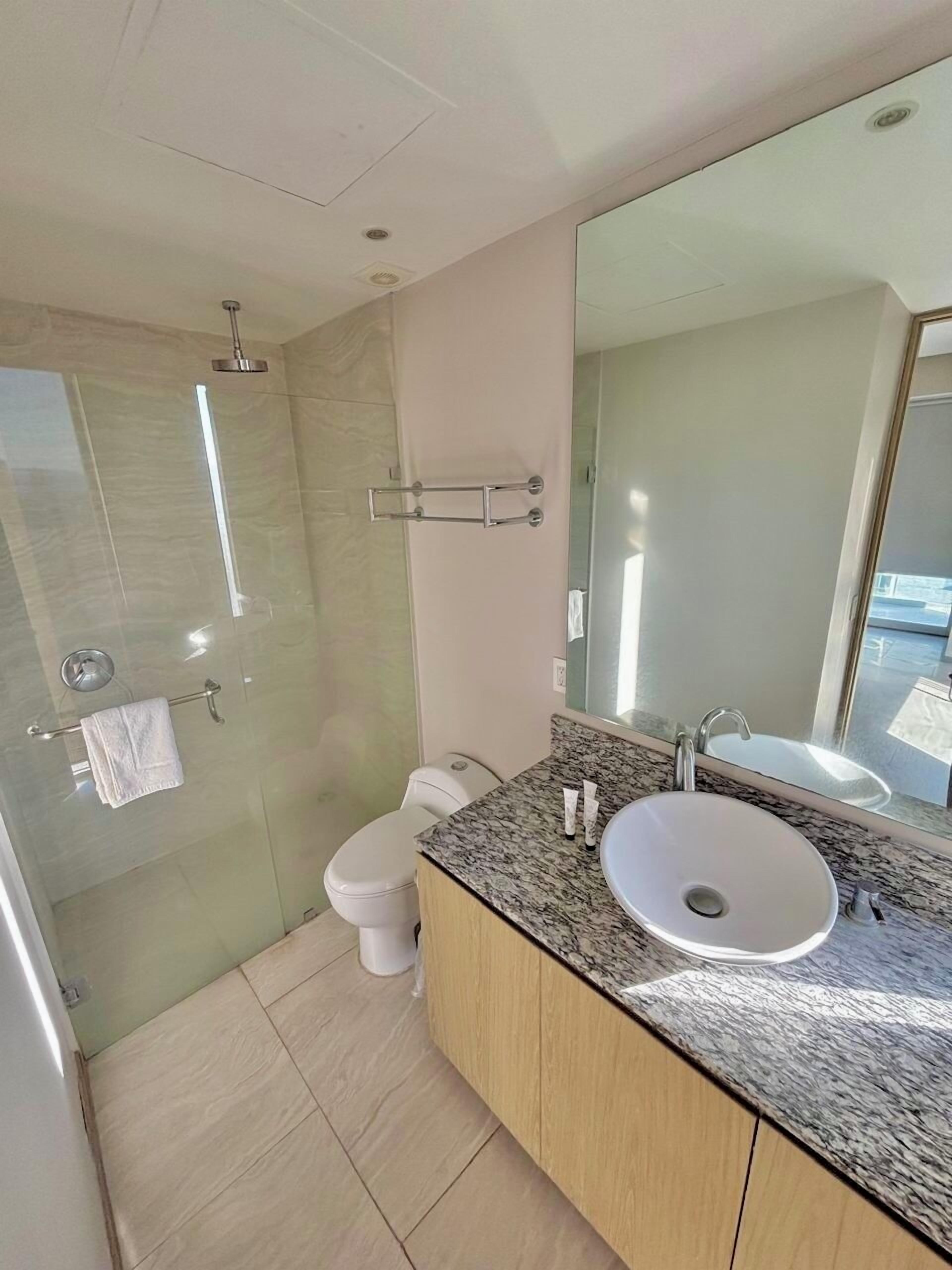 Ein modernes Badezimmer mit einer Duschkabine, einer Toilette und einem Waschtisch mit Waschbecken und Spiegel.