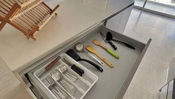 A modern kitchen with a built-in drawer containing kitchen utensils and a wooden drying rack.