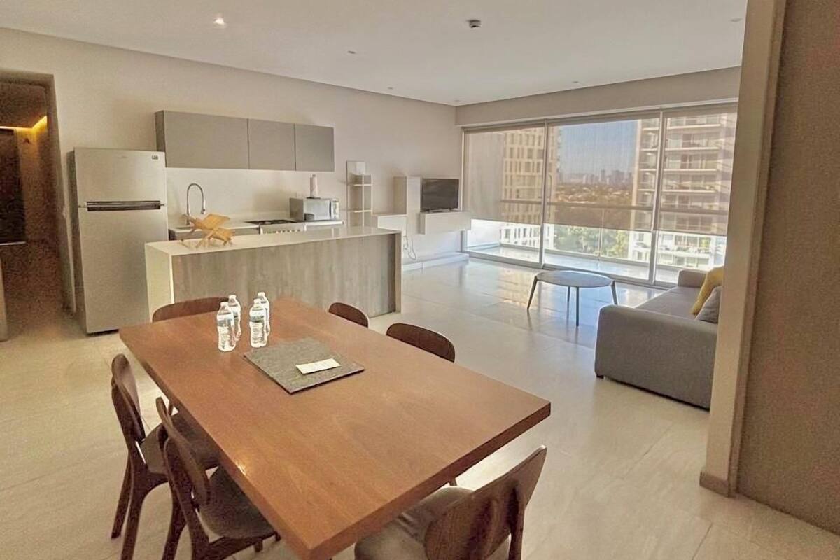 Un apartamento moderno con comedor, cocina y balcón con vista a la ciudad.