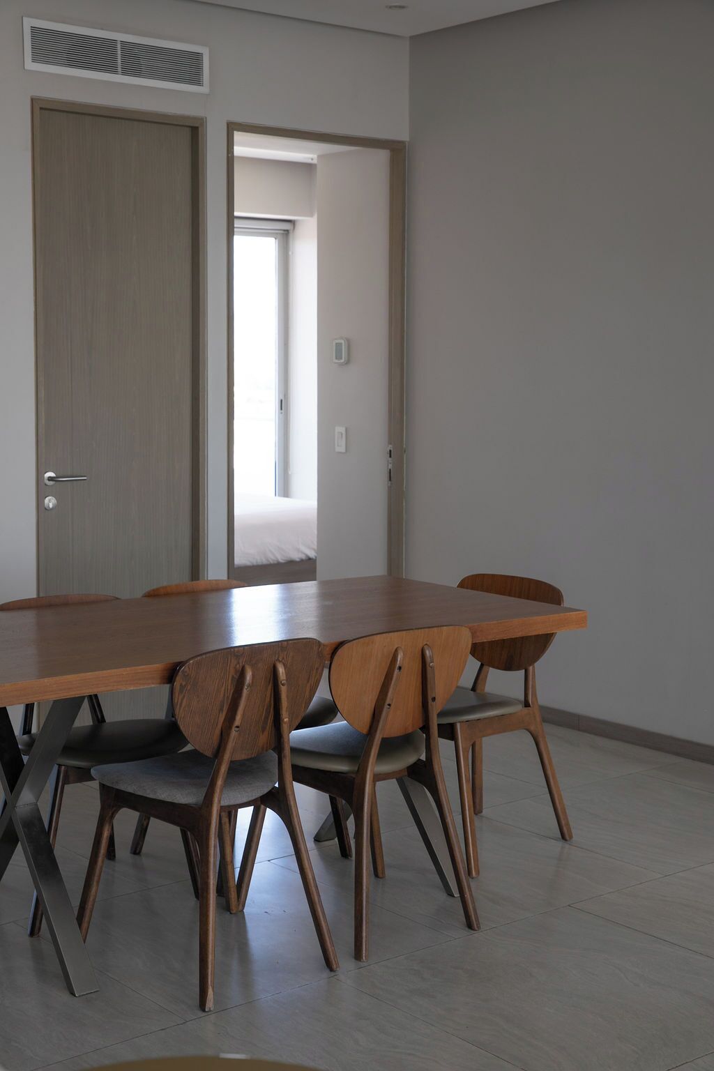 A room with a wooden dining table, six chairs, a door, and a window.