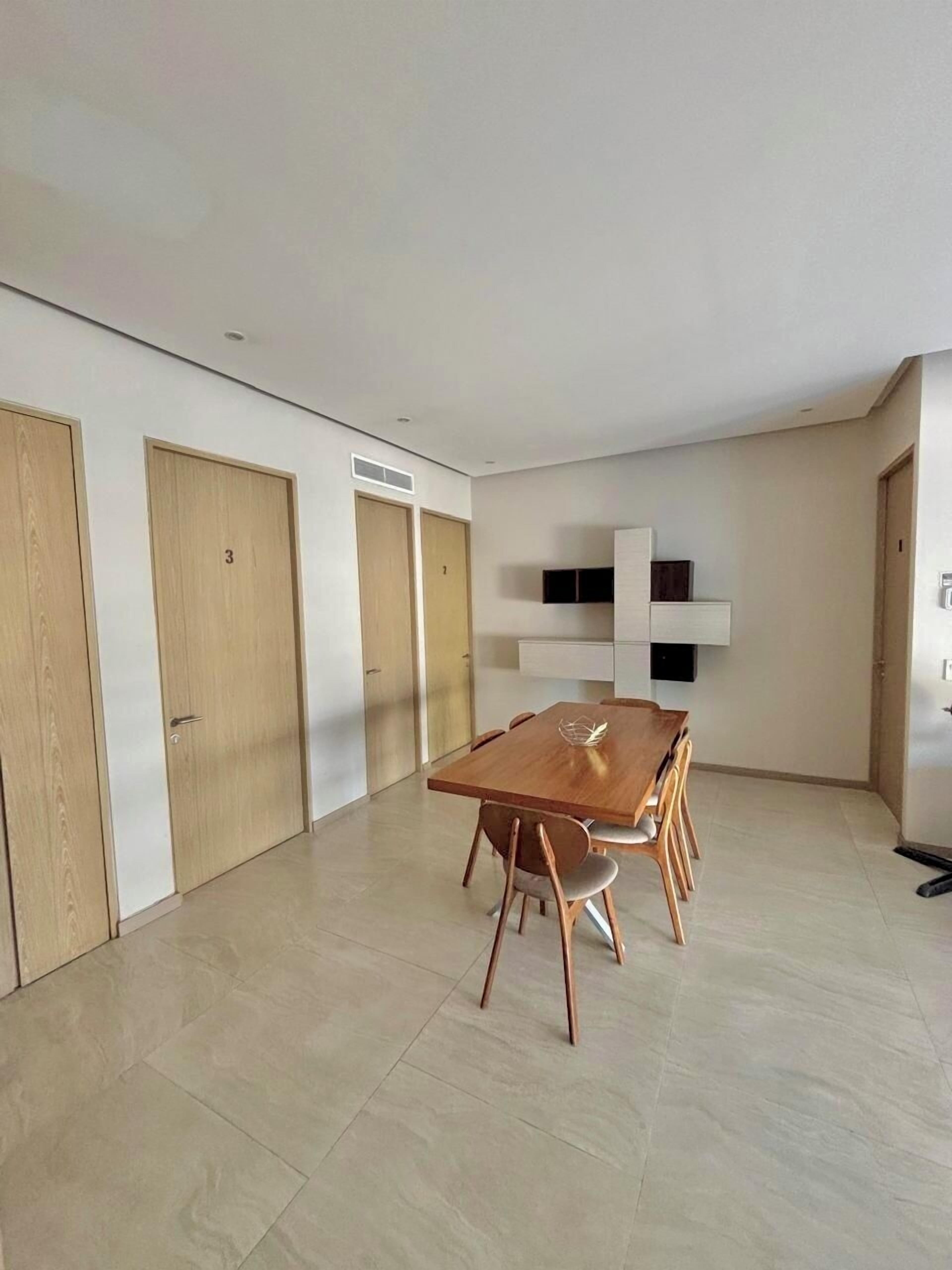A spacious room with a wooden dining table and chairs, a built-in shelf unit, and three wooden doors.