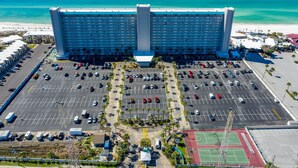 Un grand hôtel doté d’une tour centrale, d’un vaste parking et offrant une vue sur la plage.