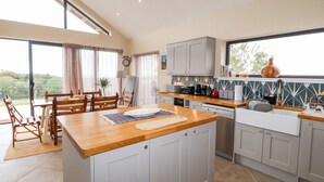 A modern kitchen with a wooden island, grey cabinets, and a large window overlooking greenery. - The Lodge (Stranraer)