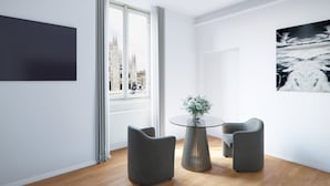 Una habitación moderna con un ventanal grande, una mesa redonda de vidrio, dos sillas grises y una obra de arte negra en la pared.