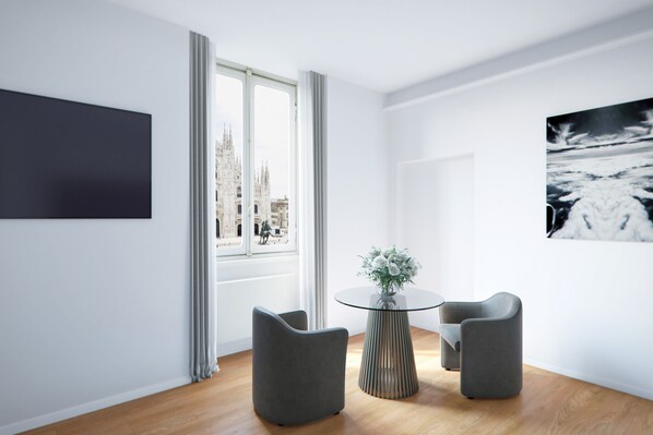 A modern room with a large window, a round glass table, two grey chairs, and a black artwork on the wall. - SCF COLLECTION - Duomo (Milan)