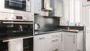 A modern kitchen with stainless steel appliances, grey cabinetry, and a black countertop. - Dancing Beggars (Dartmouth)
