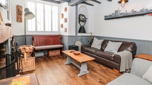 A cozy living room with a wooden bench, a brown leather sofa, and a wooden coffee table. - Dancing Beggars (Dartmouth)