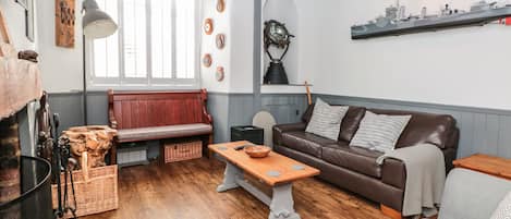 A cozy living room with a wooden bench, a brown leather sofa, and a wooden coffee table.
