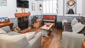 A cozy living room with a fireplace, wooden furniture, and a television. - Dancing Beggars (Dartmouth)