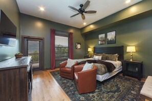A bedroom with a bed, two chairs, a desk, a ceiling fan, and two bedside lamps. - Best View in Smokies Modern Lux Pool Games Hot Tub (Sevierville)