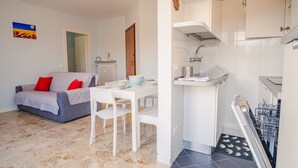 A compact living space with a sofa, dining table, and kitchenette.
