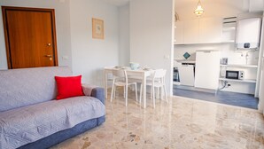 A compact living space with a sofa, dining table, and a kitchenette.