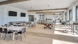 Una habitación amplia con mesa de billar, futbolín y mesa de ping pong.