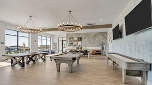 Un espacio interior amplio con mesa de billar, una larga mesa de comedor y zona de bar.