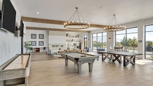 Un área interior espaciosa con mesa de billar, mesa de futbolín y mesa de billar. Amplias ventanas ofrecen luz natural y vistas al exterior.