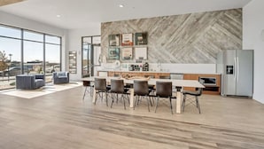 Una cocina moderna con una mesa de comedor grande, electrodomésticos integrados y una pared decorativa de madera en patrón de espiga.