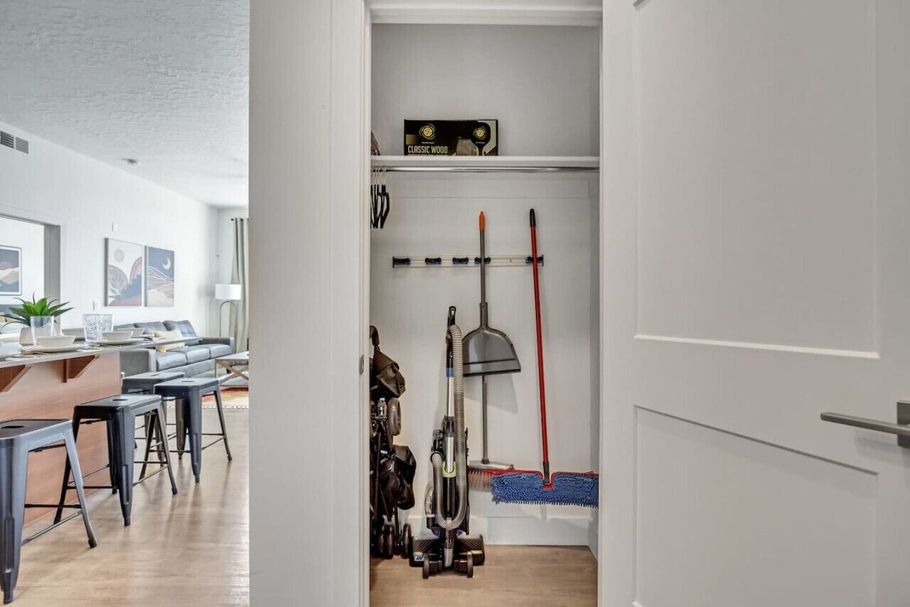 A modern kitchen with a wooden countertop, bar stools, and a hanging rack with kitchen utensils.