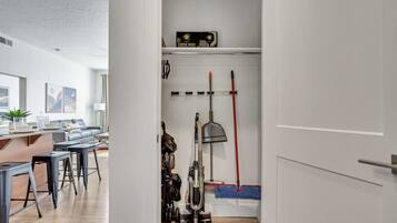 A modern kitchen with a wooden countertop, bar stools, and a hanging rack with kitchen utensils.