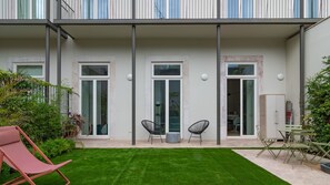 A modern building with a flat roof, large windows, and a small courtyard with a lawn and seating area.
