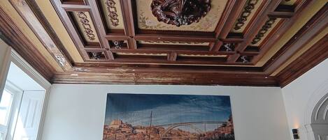 A ceiling with intricate woodwork and a large painting of a river scene.