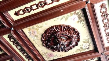 A ceiling with intricate wooden carvings and a floral-patterned panel.