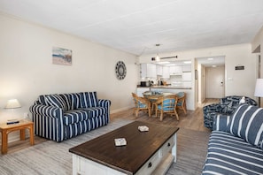 A living room with striped sofas, a coffee table, and a dining area with chairs and a table. - Direct Oceanfront Boardwalk - Steps To The Beach (Ocean City)