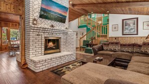 Ein gemütliches Wohnzimmer mit Kamin, Holzböden und einer Treppe, die zu einer oberen Ebene führt.