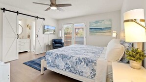 A bedroom with a bed, a ceiling fan, a nightstand, a lamp, a chair, and a window with blinds. - 2 Blocks from the Beach: The Coquina Cottage (Jacksonville Beach)