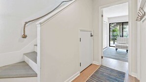A staircase leading to a door, a rug on the floor, and a view of an outdoor area with a chair. - 2 Blocks from the Beach: The Coquina Cottage (Jacksonville Beach)