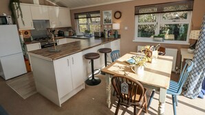 A kitchen with white cabinets, a wooden countertop, and a dining area with a table and chairs. - 1 Hornbeam Lodge (Narberth)