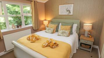 A neatly arranged bedroom with a bed, bedside lamps, a nightstand, and a window with curtains.