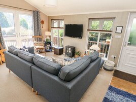 A living room with a sectional sofa, a wooden chair, a TV, and a fireplace.