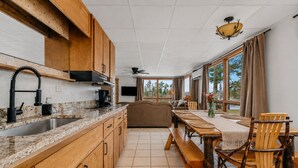A kitchen with wooden cabinets, a granite countertop, a built-in oven, and a dining area with a wooden table and chairs.